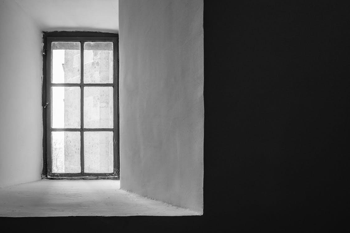 A grayscale picture of a closed glass window in a room