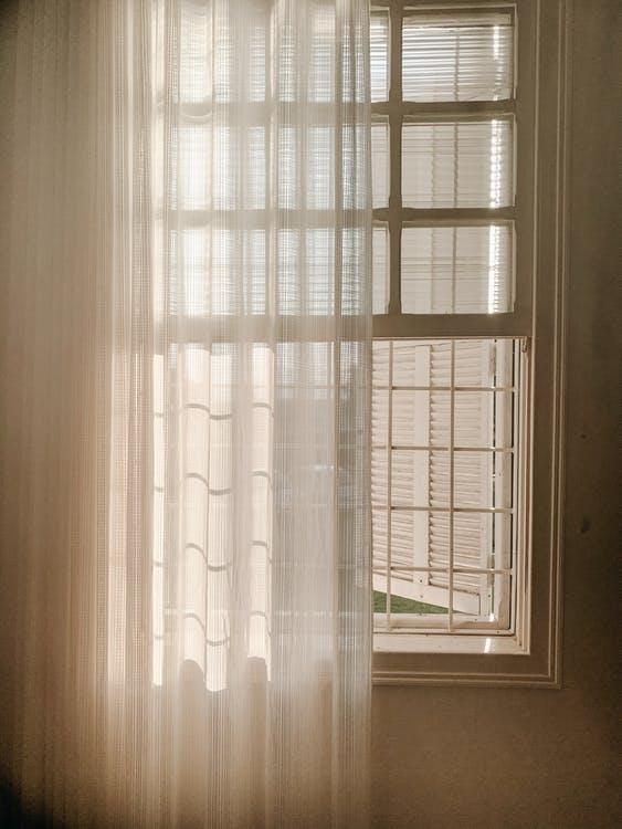 An open white glass window with sheer curtains