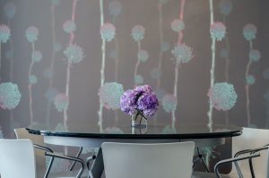 A pink and white themed room with flowers on top of a glass top table