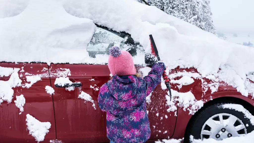 Child Clearing Heavy Snow from Red Car - Winter-Proof Your Windshield