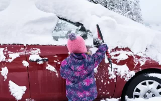 Child Clearing Heavy Snow from Red Car - Winter-Proof Your Windshield
