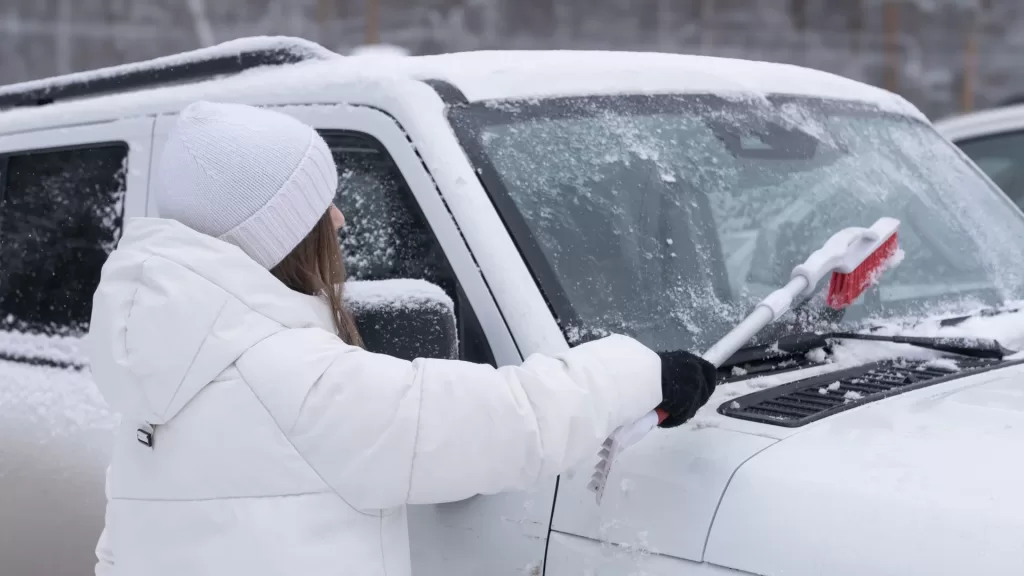 Woman Brushing Snow Off SUV Windshield